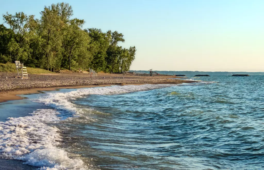 Deserted beach with lifeguard chairs and trees in background on Presque Isle on Lake Erie