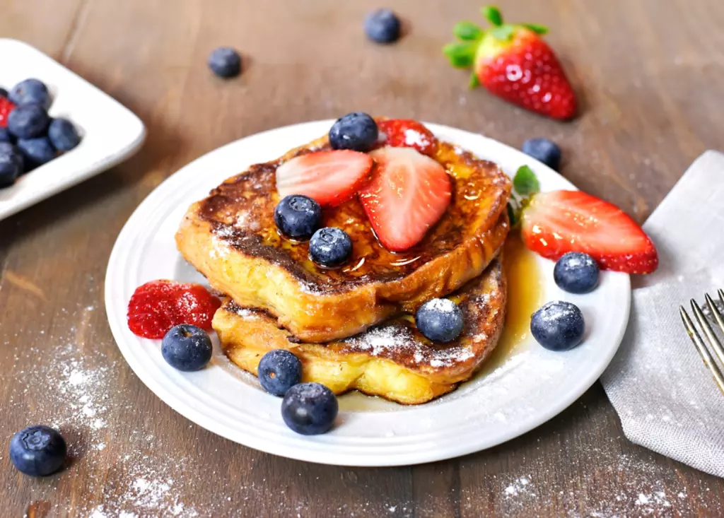 French toast with syrup, strawberries, and powdered sugar.