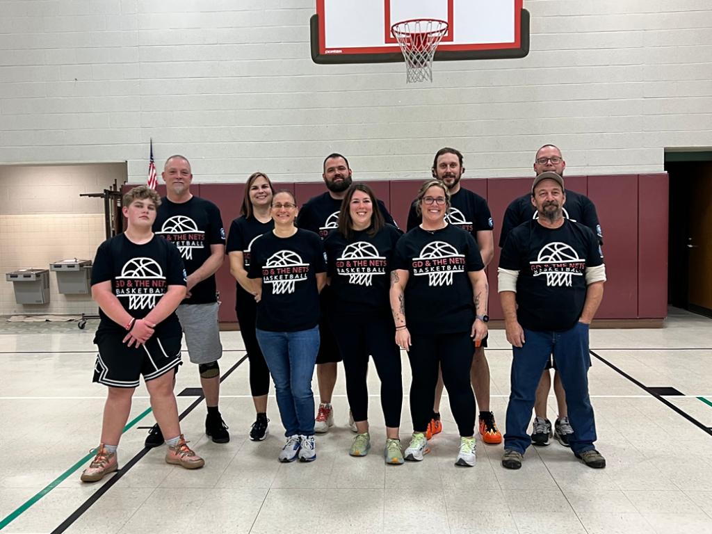 Group of Grand Design employees pose for a photo at a basketball game while volunteering with ADEC. 