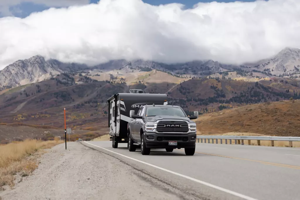 Grand Design Imagine XLS being towed by a truck with the mountains in the background. 