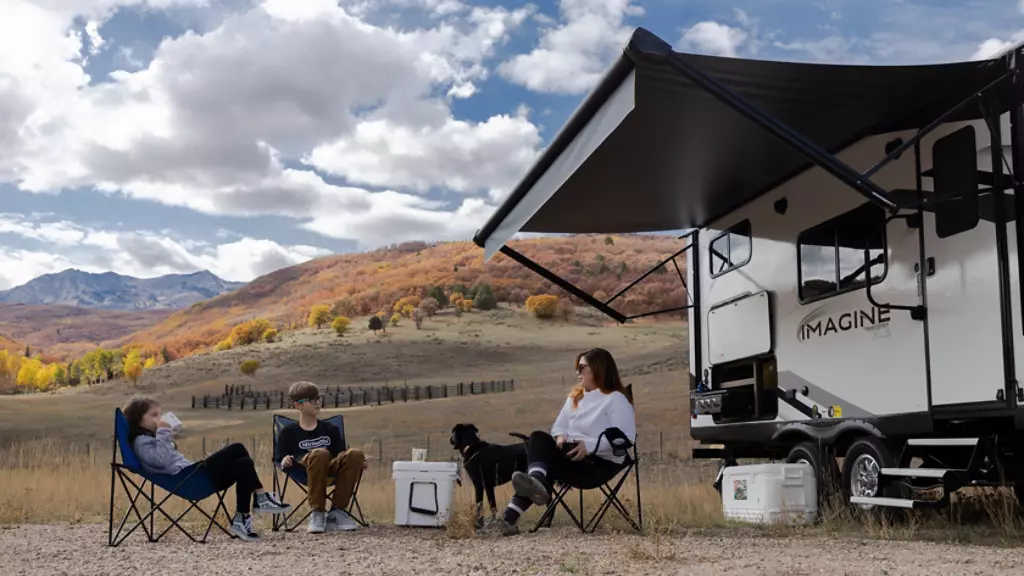 Mom with two children sitting in camping chairs in front of a Grand Design Imagine XLS. 