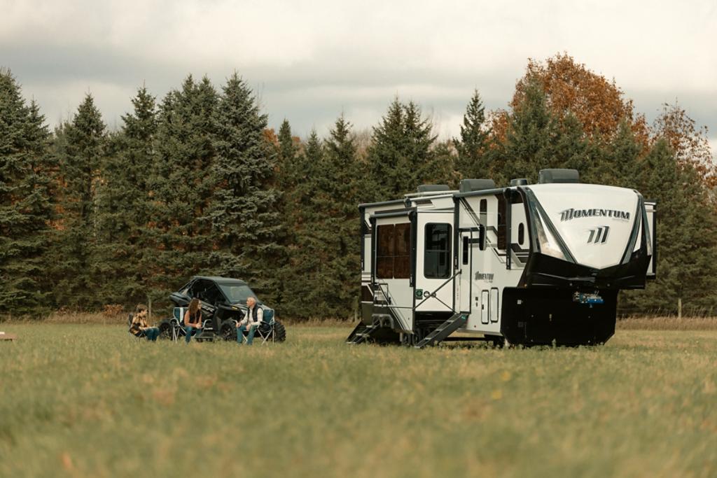 Family gathered around fire in front of a Reflection fifth wheel