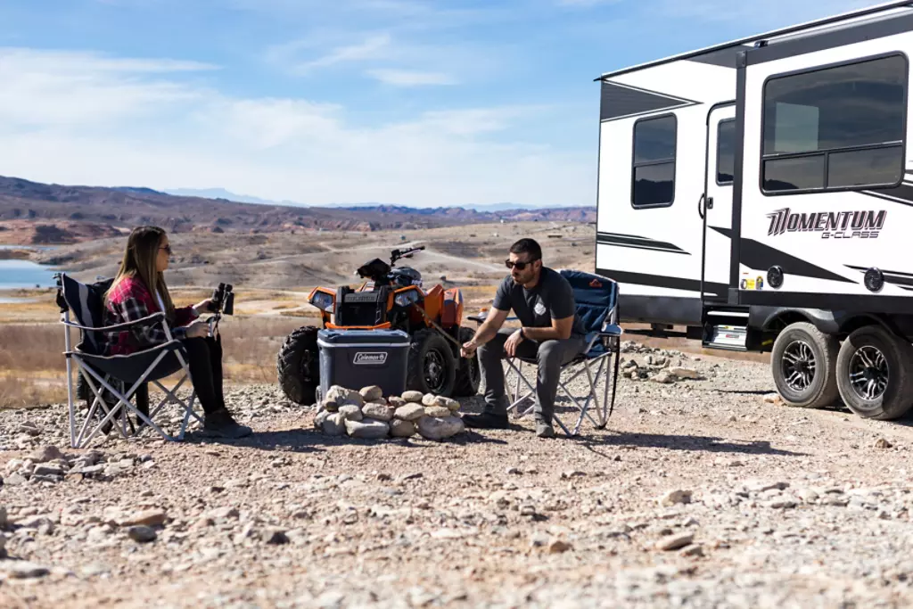 Couple starting a fire in front of camper.