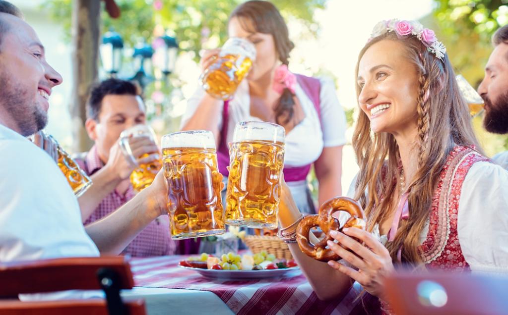 Couple looking at each other clinking glasses with huge amounts of beer in Bavarian pub