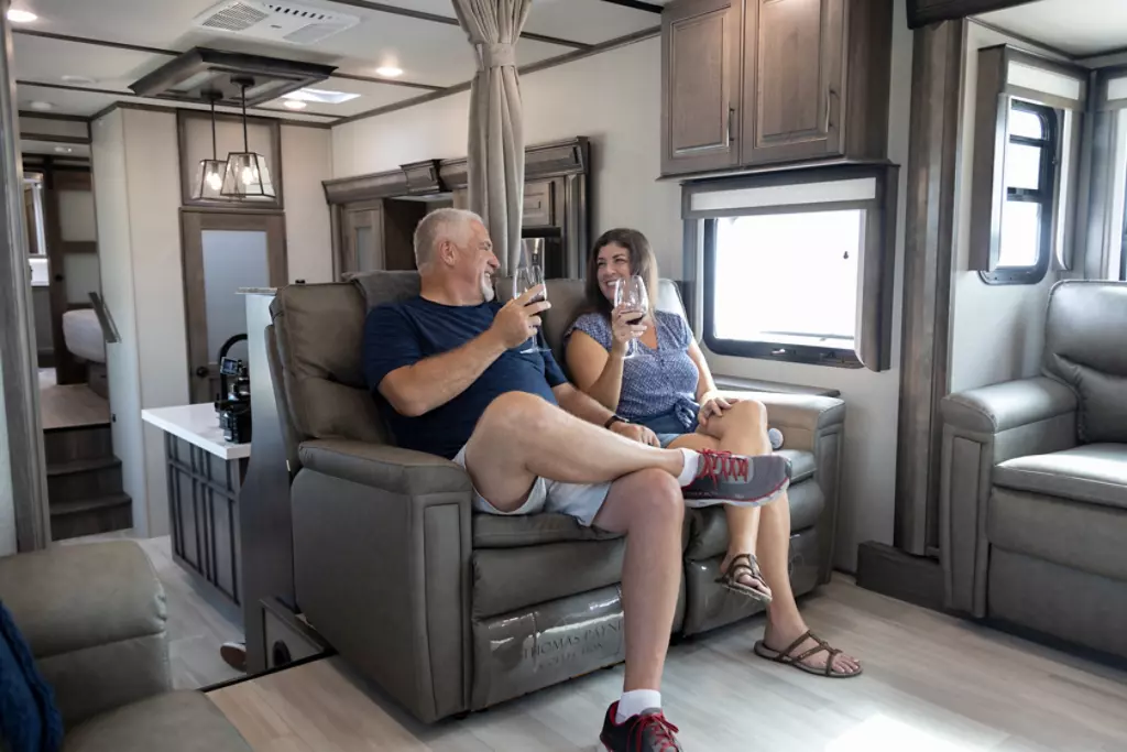 Couple sitting inside of the living room of a Grand Design Solitude.