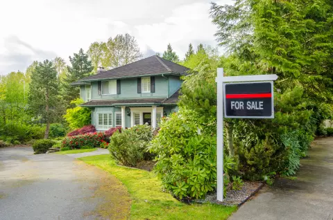 Picture of two-story house that has a "for sale" sign in the front. 