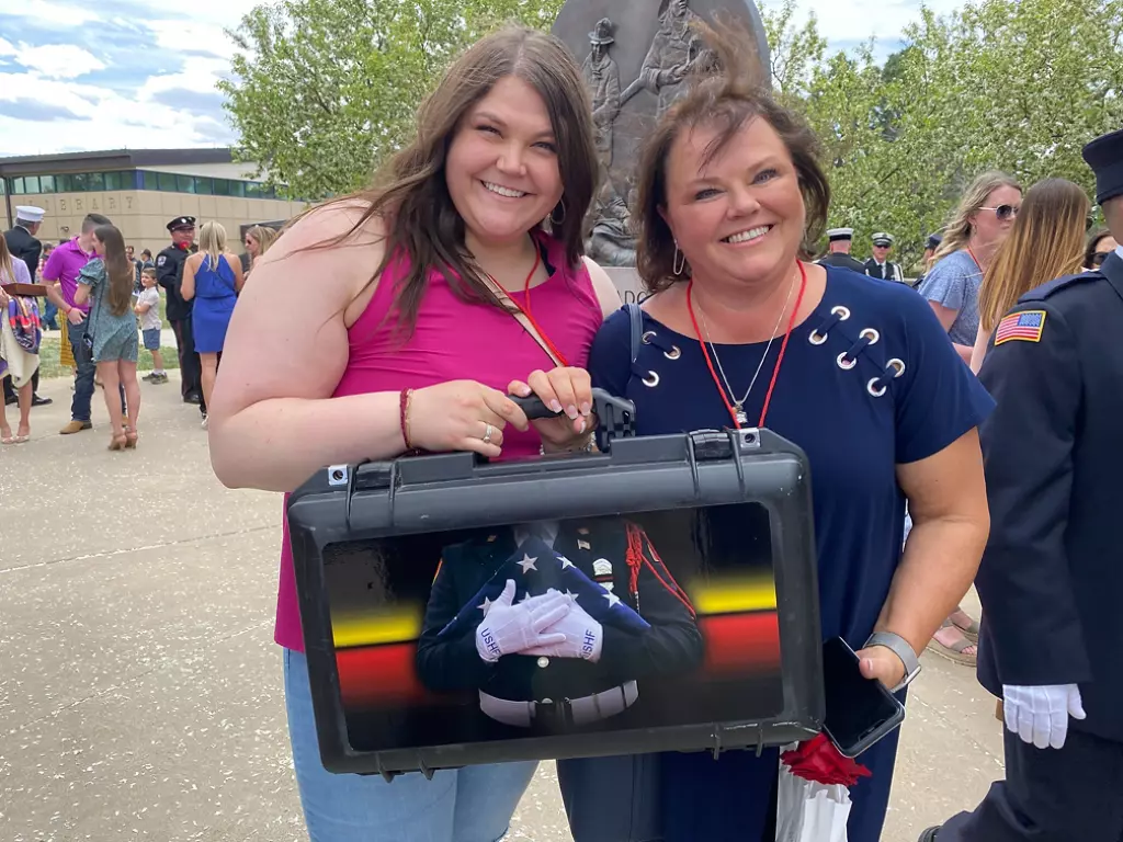 Women holding flag case.