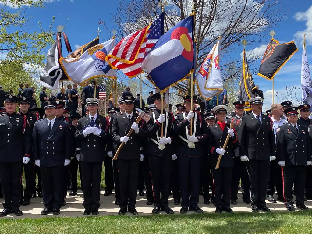 First responders in formation, holding flags. 