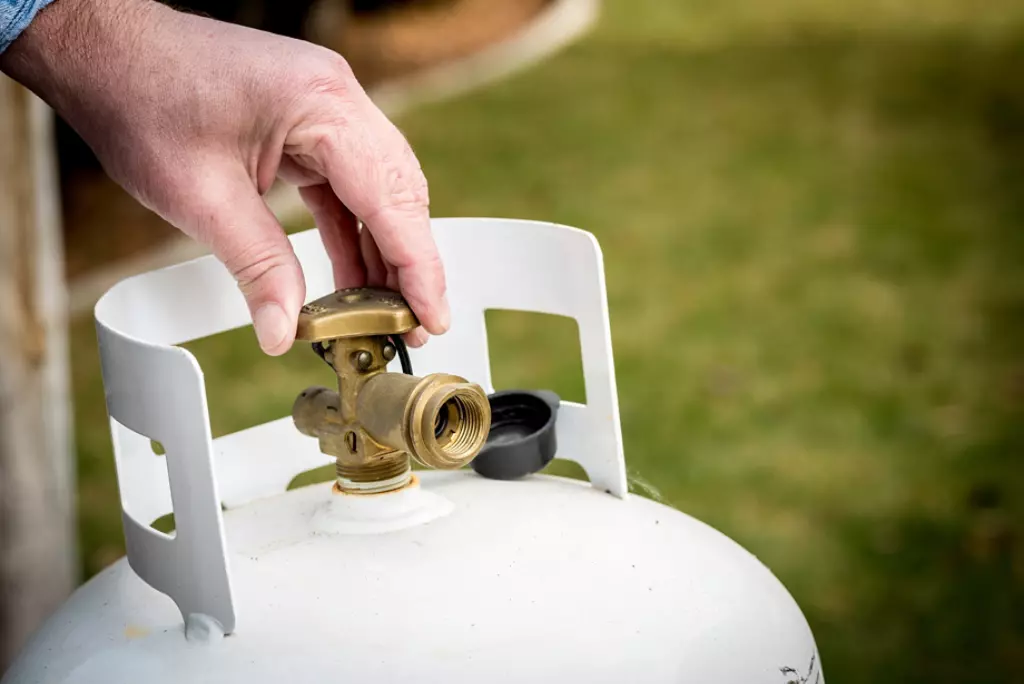 Man turning valve on propane tank.