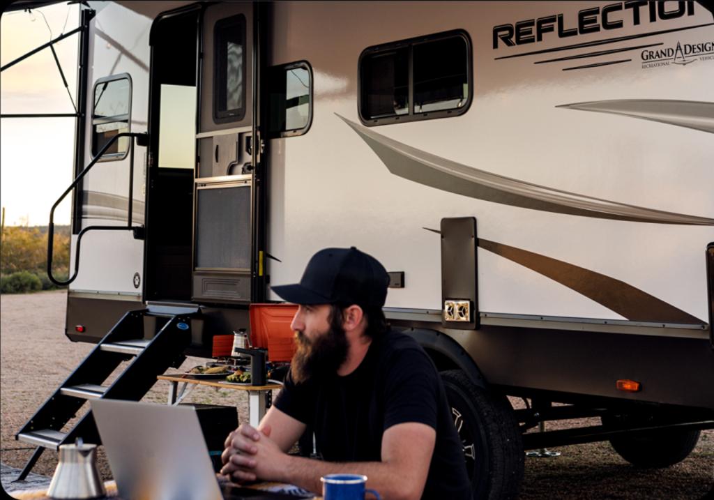 Camper working on a computer in front of his RV. 