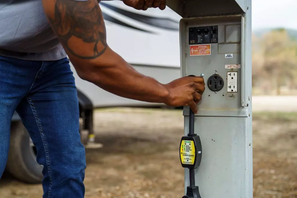 RV surge protector being plugged in by man.