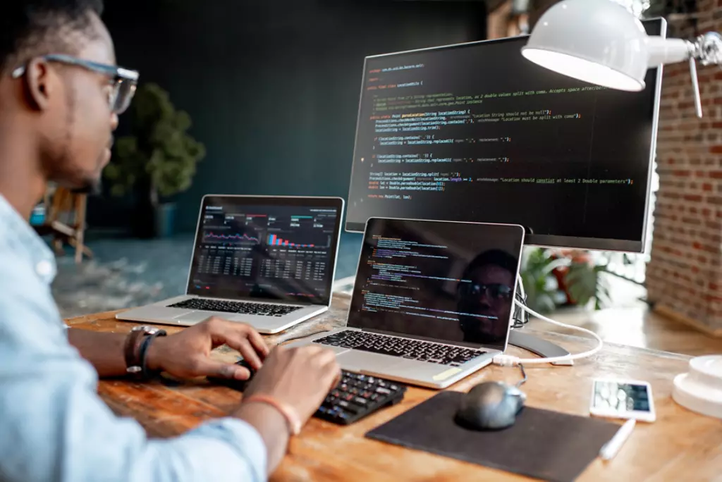 Man in front of computer coding. 